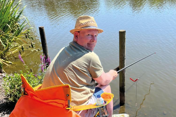 Photo of male resident sat fishing in the sun