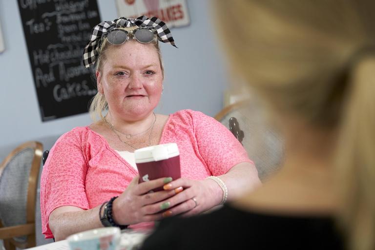 female service user sat with a cup of coffee