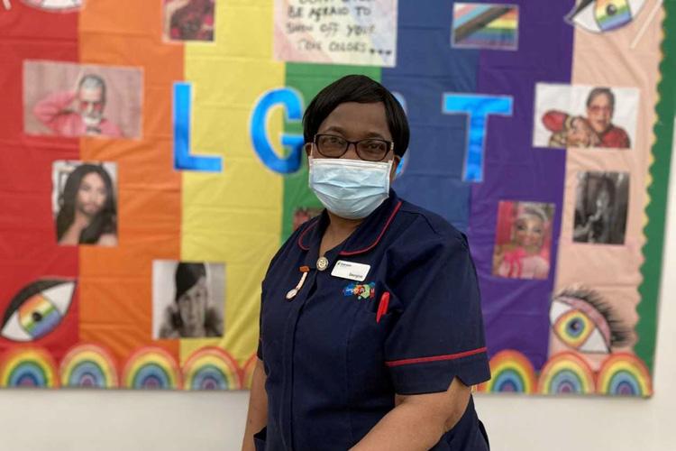 Nurse stood in front of LGBT notice board