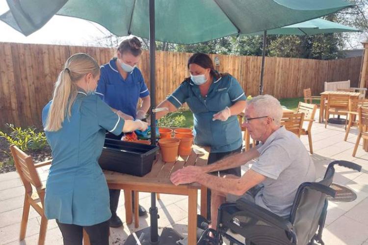 Male service user gardening with health care assistants in the sun