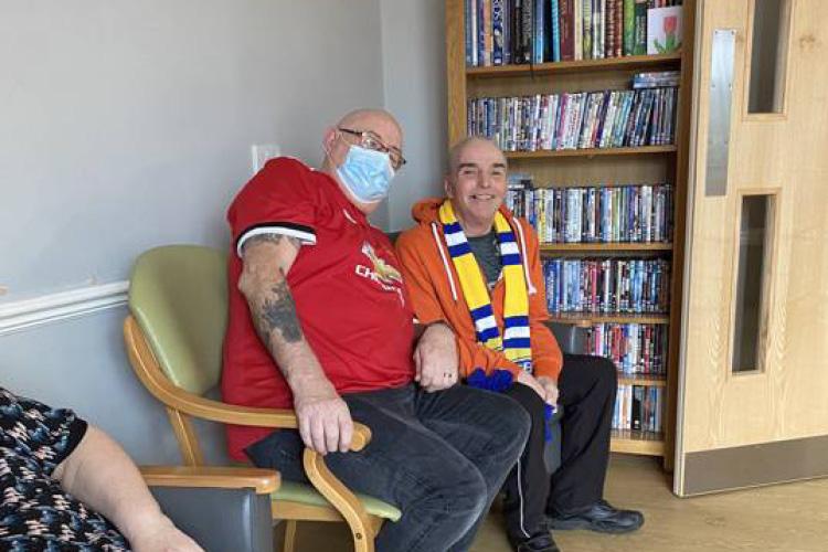 Care home resident and staff member watching football