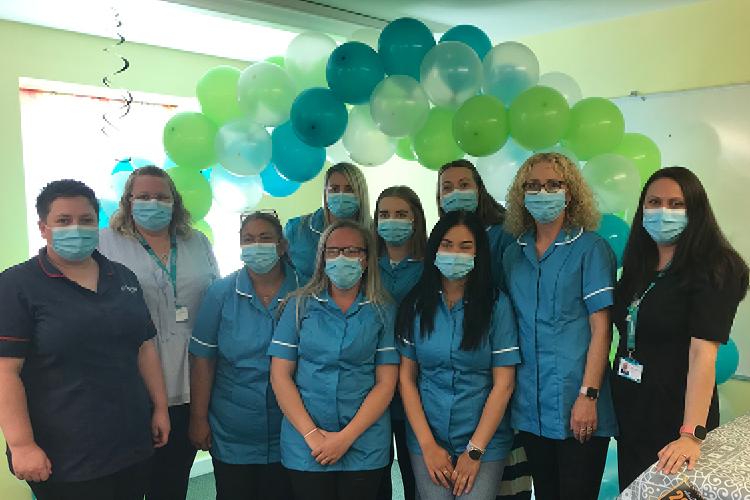 Picture of Care Practitioners stood under a balloon arch