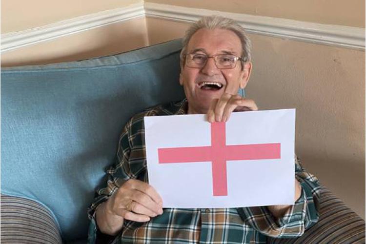 Male service user holding England flag watching football