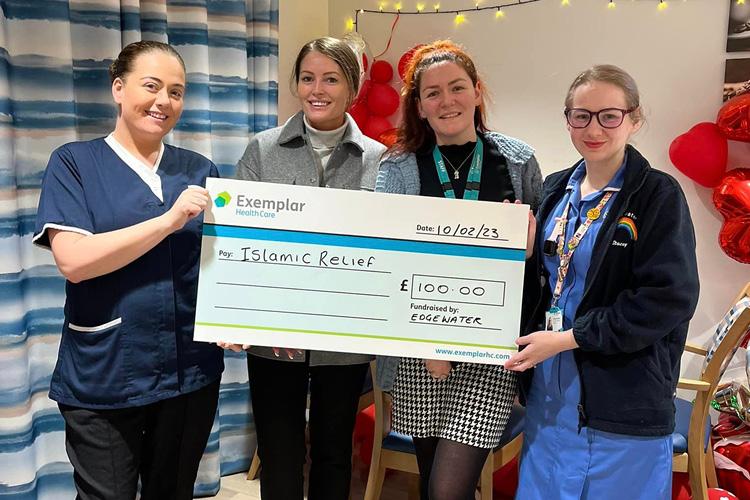 Four care workers with giant cheque for charity