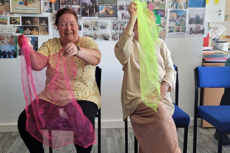 Two service users taking part in a dance class with props