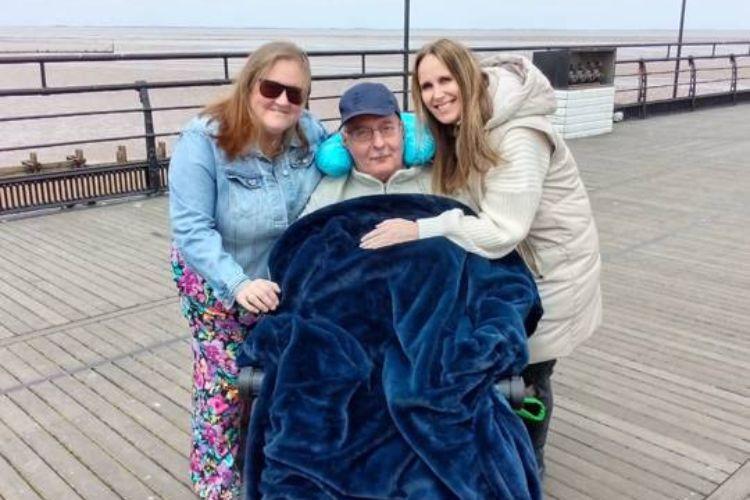 Male service user at the seaside with two family member