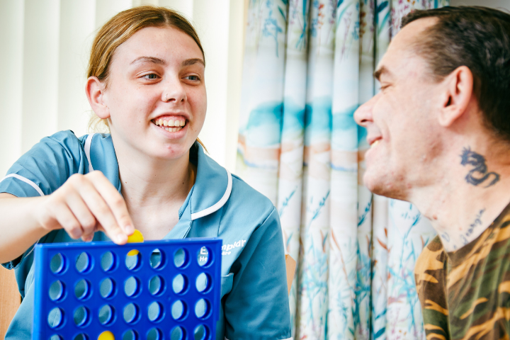 smiling Health Care Assistant playing connect 4