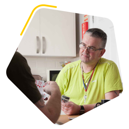 Male service user playing cards with carer